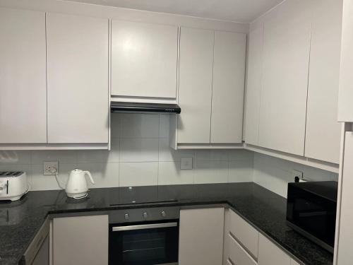 Una cocina con gabinetes blancos y una encimera negra. en Balgowan Estate Sandton, en Johannesburgo