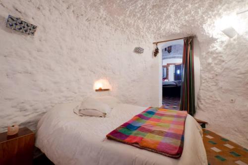 a bedroom with a bed with a colorful blanket on it at La Constanza Casa Cueva by ASH in Granada