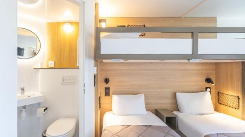 a small room with two beds and a toilet at Premiere Classe Boissy St Leger in Boissy-Saint-Léger
