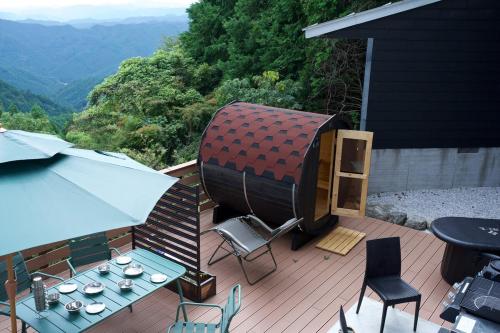 a patio with a table and chairs and an umbrella at フォレスタ風影山荘 in Hanno