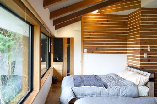 a bedroom with a bed and a large window at フォレスタ風影山荘 in Hanno