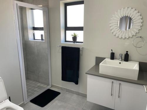 een witte badkamer met een wastafel en een douche bij Coastal Charm St Francis Bay in Vosburg