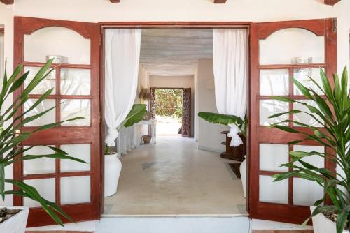 une porte ouverte menant à un couloir orné de plantes dans l'établissement Crystal Bay Resort, à Watamu