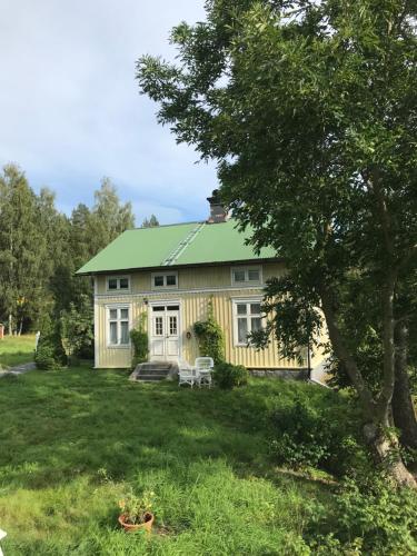 una gran casa amarilla con techo verde en Lakeside Guesthouse, Lillstugan, en Ramvik