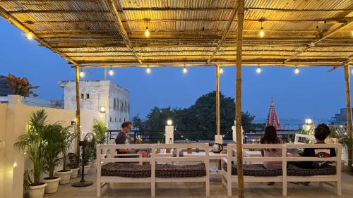 a group of people sitting at a table under a pergola at SAIR Hostel, Varanasi - 100m from Assi Ghat in Varanasi