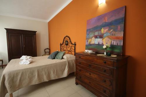 a bedroom with a bed and a dresser with a painting at 6 appartamenti per gruppi fino a 20 persone in Viarigi