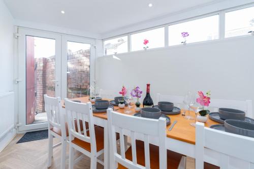 a dining room with a wooden table and white chairs at Open Mind Property - 4BR, 17 Guests & Free Parking in Portsmouth