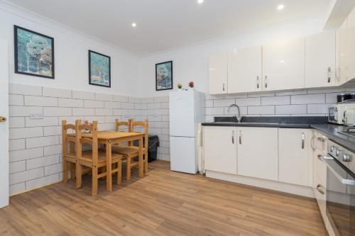 a kitchen with white cabinets and a table and chairs at Open Mind Property - 4BR, 17 Guests & Free Parking in Portsmouth