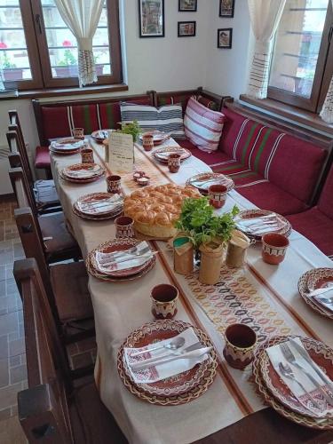 a long table with plates of food on it at Къща за гости Начовата къща Стойките, Пампорово in Vodata