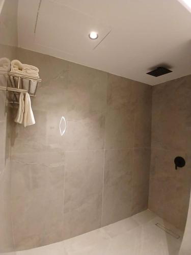 a bathroom with a shower with towels on a wall at رؤوم إن للشقق المخدومة -شقراء-Raoum Inn Serviced Apartments-Shaqraa in Shaqra