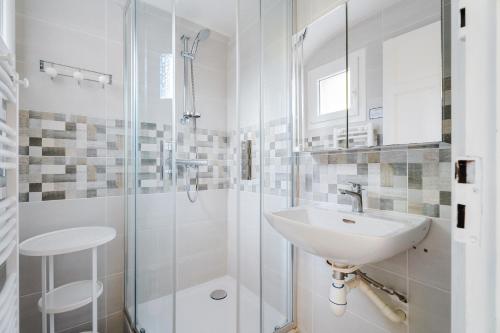 a white bathroom with a sink and a shower at Maison 50m de la mer parking privé in Cancale