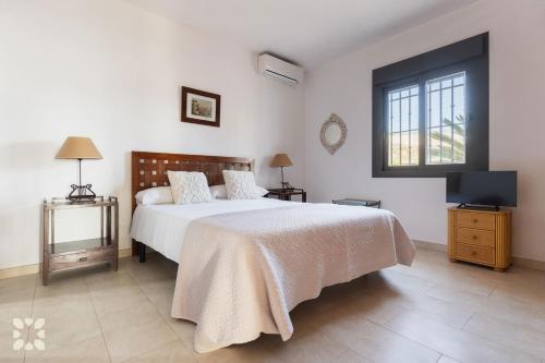 ein Schlafzimmer mit einem Bett und einem Fernseher darin in der Unterkunft Villa Sapphire by Abahana Villas in Teulada