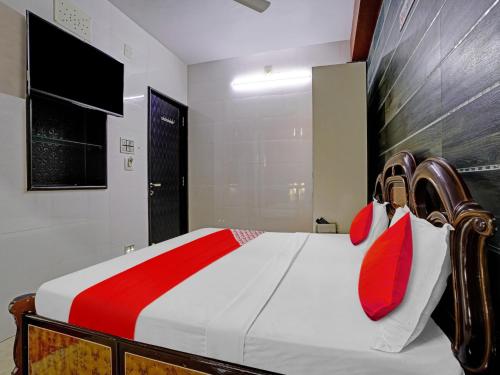 a bedroom with a bed with red and white pillows at Hotel O Gangeshwar in Anand