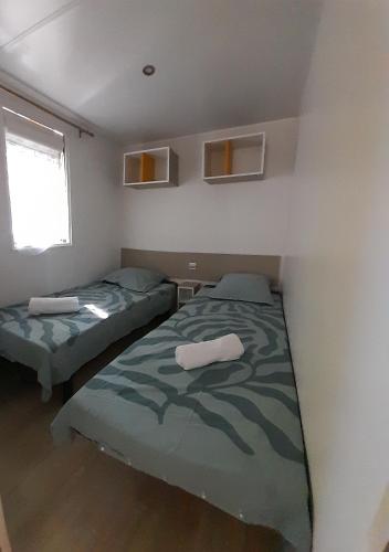 a bedroom with two beds and a window at mobilhome 508 in Parentis-en-Born
