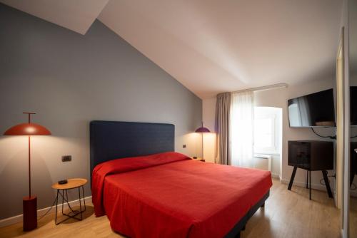 a bedroom with a red bed and a television at Albergo Alla Posta in Trieste