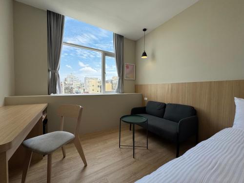 台南市にあるYoshi Hotel Xinmei Streetのベッドとソファと机のある寝室