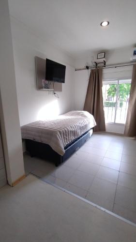 Un dormitorio con una cama y un televisor en la pared. en Loft San Lorenzo, en Bahía Blanca