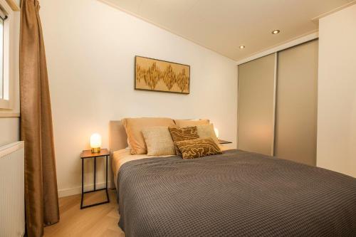 a bedroom with a bed and a lamp on a table at Veluwepark de Bosgraaf in Apeldoorn