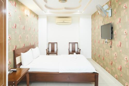 a bedroom with a bed and a tv on a wall at Quang Huy Hotel in Ho Chi Minh City