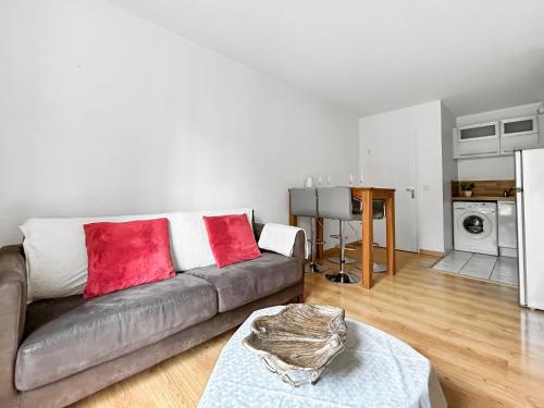 een woonkamer met een bank met rode kussens erop bij Sweet Dream Chessy-Near Disney, Parking privée in Chessy