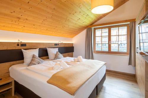 a bedroom with a large white bed with a wooden ceiling at Landal Brandnertal in Bürserberg