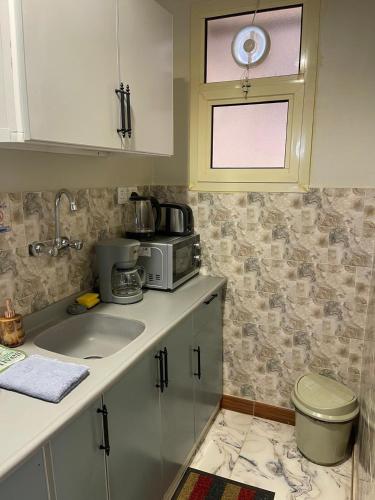 a kitchen with a sink and a microwave at أي رووم سويتس للشقق المخدومة in Sakakah