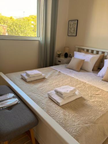 a large bed with two towels on top of it at Mesogaia Home Near ATH Airport in Markopoulo