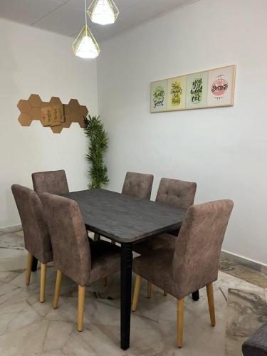 a dining room table and chairs with a table and a plant at Mus Lim Homestay Aqil Bandar Puncak Alam in Bandar Puncak Alam