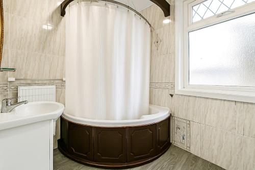 ein Badezimmer mit Badewanne und Waschbecken und einem Fenster in der Unterkunft Spacious charming house near Heathrow in Feltham