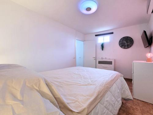een slaapkamer met een wit bed en een klok aan de muur bij René in Los Realejos