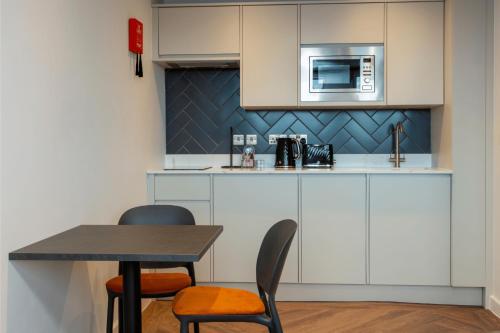 a kitchen with a table and chairs and a microwave at Station Suites Aparthotel in Middlesbrough