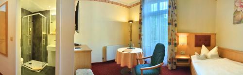 a hotel room with a bed and a bathroom at Hotel-Pension Vier Jahreszeiten in Bad Elster