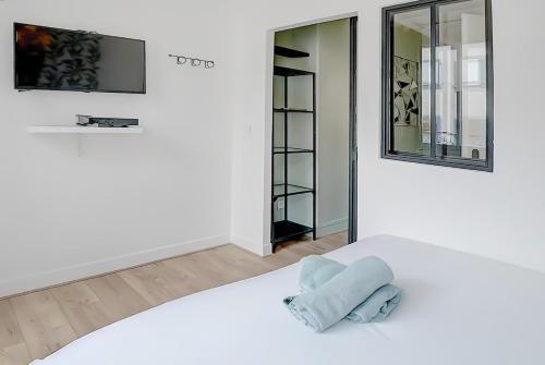 Una habitación blanca con una cama y un espejo. en L'atelier de Charpennes, en La Celle-sous-Gouzon