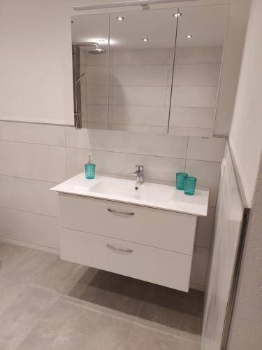 a white bathroom with a sink and a mirror at Ferienwohnung Bergstraße in Extertal