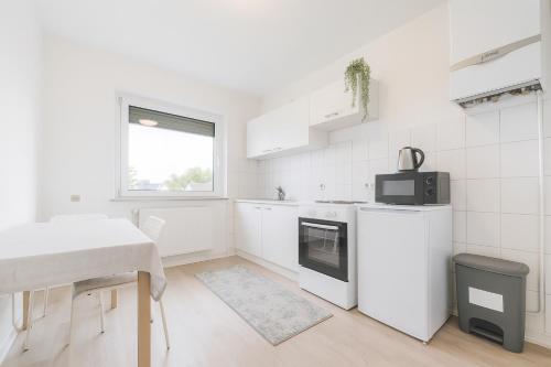 eine weiße Küche mit weißen Geräten und einem Tisch in der Unterkunft Köln Frechen 44 in Frechen