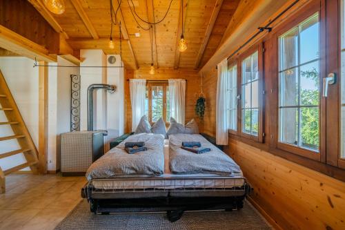 Cama en habitación con paredes y ventanas de madera en Mountain Loft - Where Design Meets Nature, en Axalp
