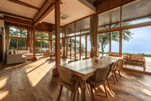 a dining room with a wooden table and glass windows at Villa Selatan in Jimbaran