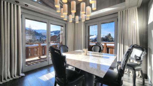 une salle à manger avec une table et des chaises et une grande fenêtre dans l'établissement Chalet Crystal, à Megève
