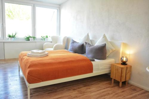 a bedroom with a bed with an orange blanket and a chair at Apartment mitten in Rosenheim in Rosenheim
