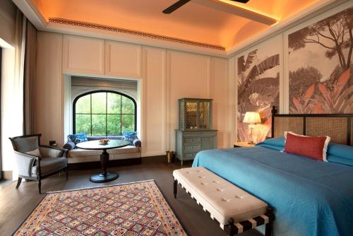 a bedroom with a bed and a table and a chair at The Oberoi Rajgarh Palace in Rājgarh
