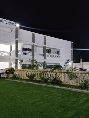a white building with a lawn in front of it at Boho Comfort Homes in Diani Beach