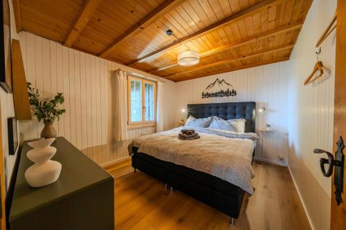 a bedroom with a large bed and a wooden ceiling at Mountain Apartment - Hot Tub & Sunset Views in Axalp