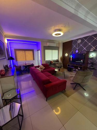 a living room with a red couch and purple lighting at Beautiful apartment in front of Playce Palmeraie Faya in Abidjan