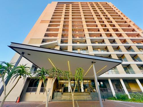 a tall building with palm trees in front of it at Menlyn Maine Residences - Kyoto king size xl bed in Pretoria