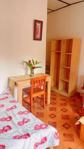 a room with a desk and a table with a vase of flowers at Garden House in Huye