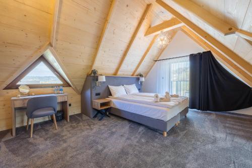 a bedroom with a bed and a desk in a attic at Apartamenty Koziniec Lux in Czarna Góra