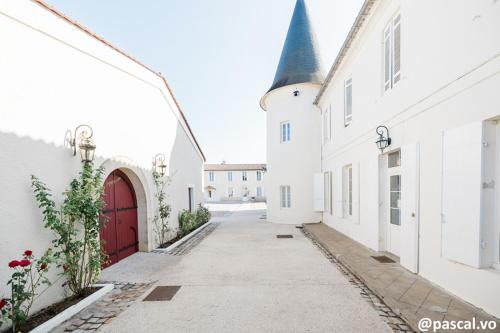 an alley with white buildings and a red door at Chambres d'hôtes du Château de Seguin in Lignan-de-Bordeaux
