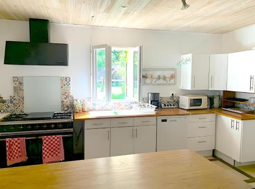 eine Küche mit weißen Schränken und einer Spüle und einem Fenster in der Unterkunft Le Gite D'origne in Origne