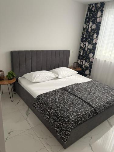 a bed with a gray headboard and white sheets and pillows at MY PLACE Il in Slavonski Brod