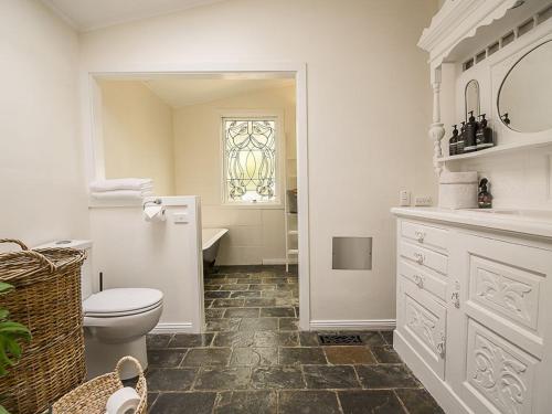 Un baño con inodoro, lavabo y ventana. en Healesville Country House, en Healesville